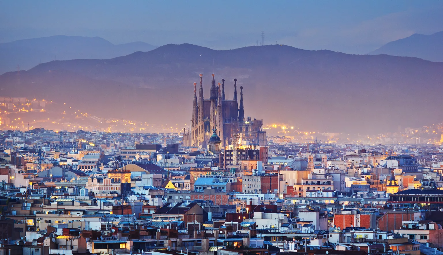 Panoramic view of Barcelona at sunset, featuring the Sagrada Família